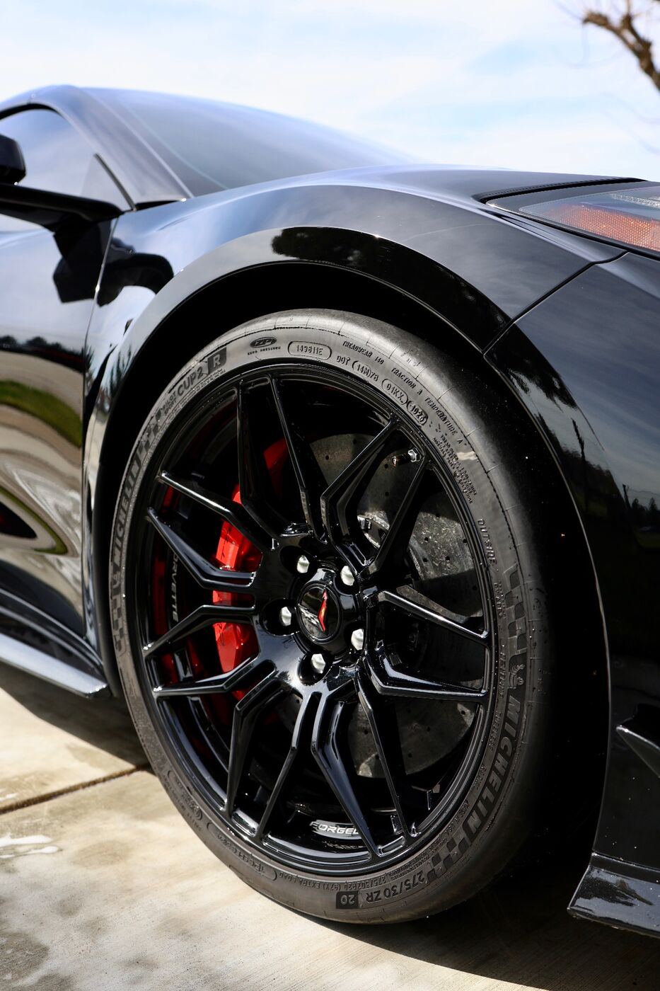 Clean gloss-black wheel with a red brake caliper and a freshly dressed tire