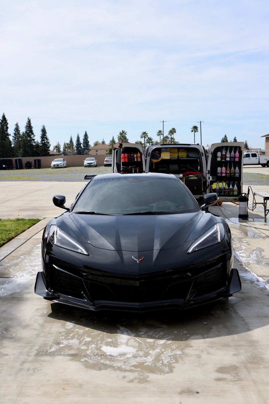 Black Corvette Z06 in a driveway with the EPC mobile detailing van's rear doors open